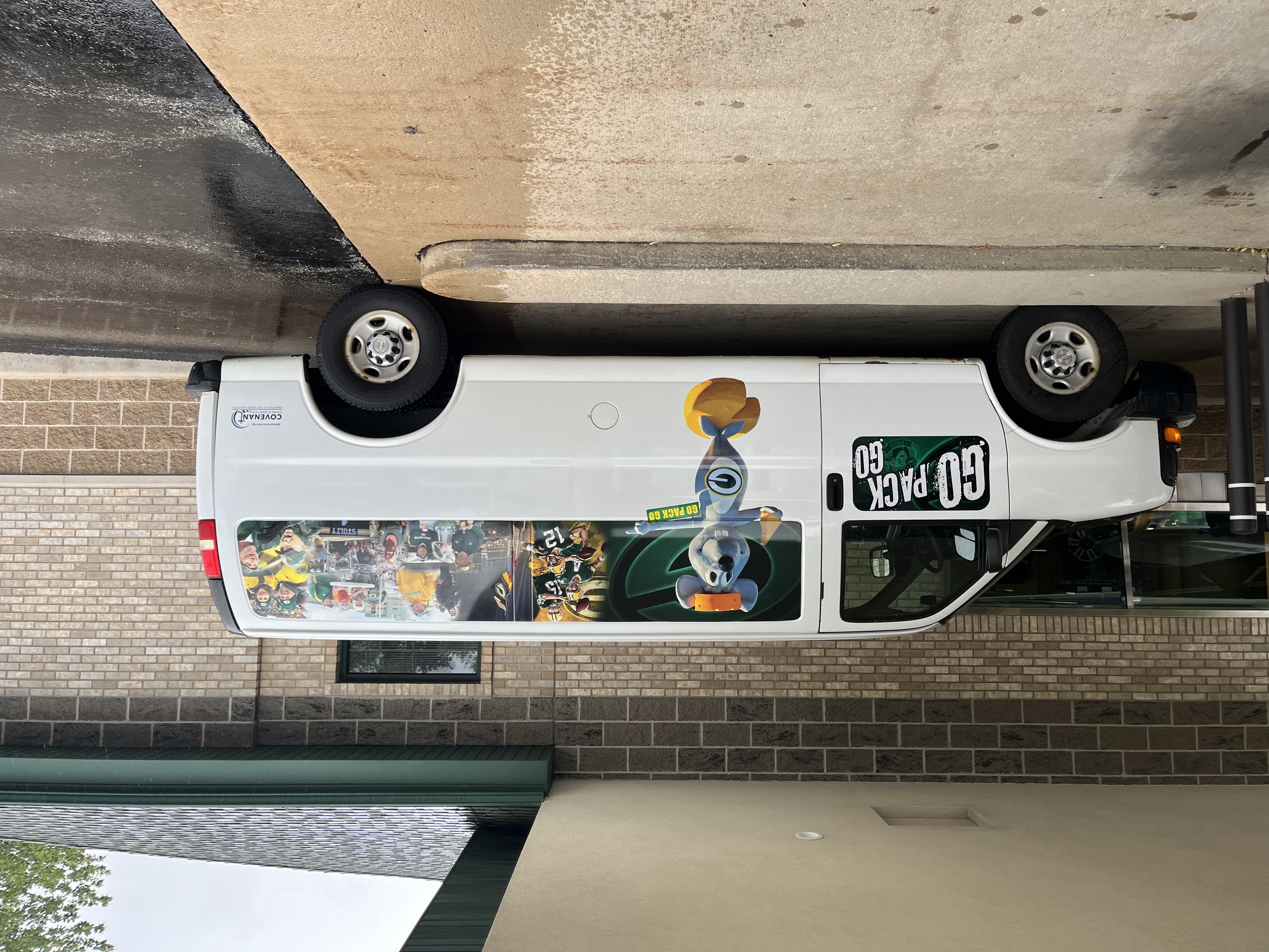 High-resolution side view of a custom Go Pack Go Packers-themed van wrap installed by Covenant Signs and Graphics