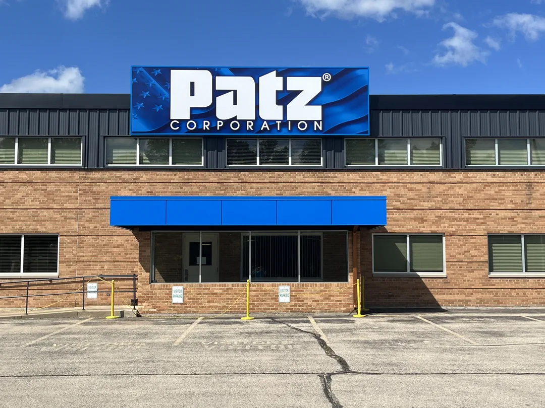 Patz Corporation blue wave building sign mounted on a brick manufacturing facility