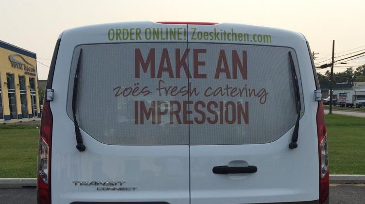 Perforated vinyl graphics installed across a vehicle window